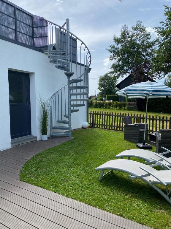 a patio with a staircase and chairs and an umbrella at Ferienhaus Lorea in Bütgenbach in Butgenbach