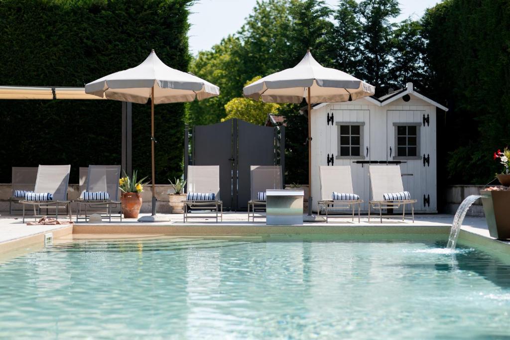 a pool with chairs and umbrellas next to a house at Residence Cà di Capri in Bussolengo