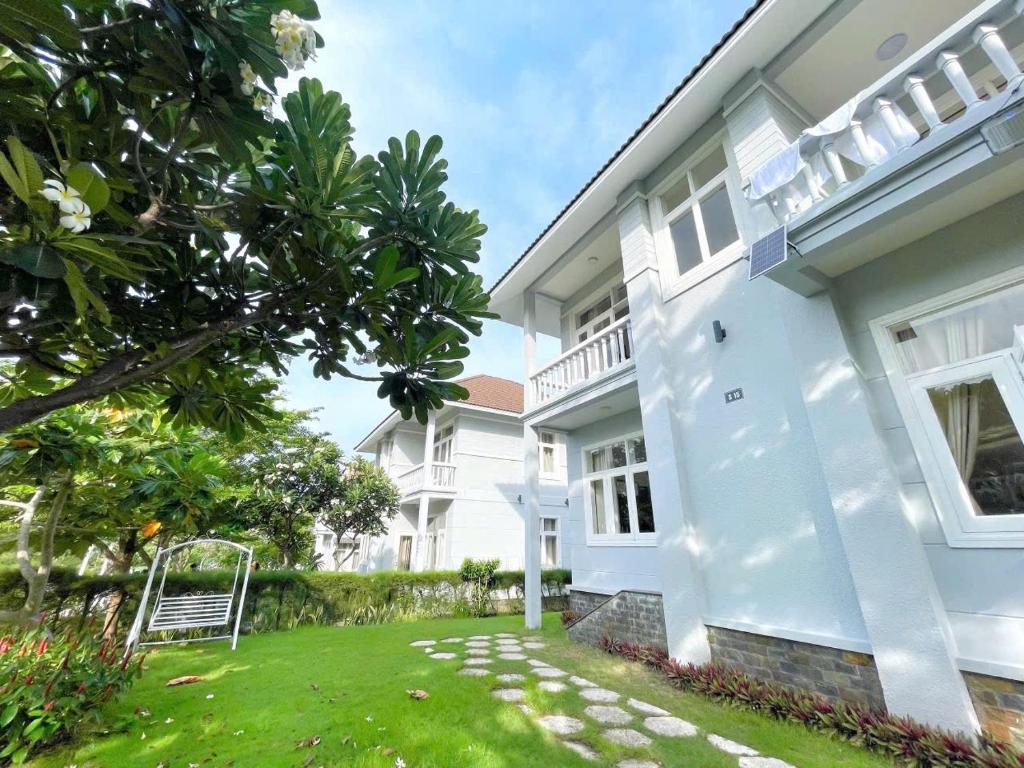 a white house with a lawn in front of it at Vila Mũi Né-Phan Thiết in Ấp Ngọc Hải