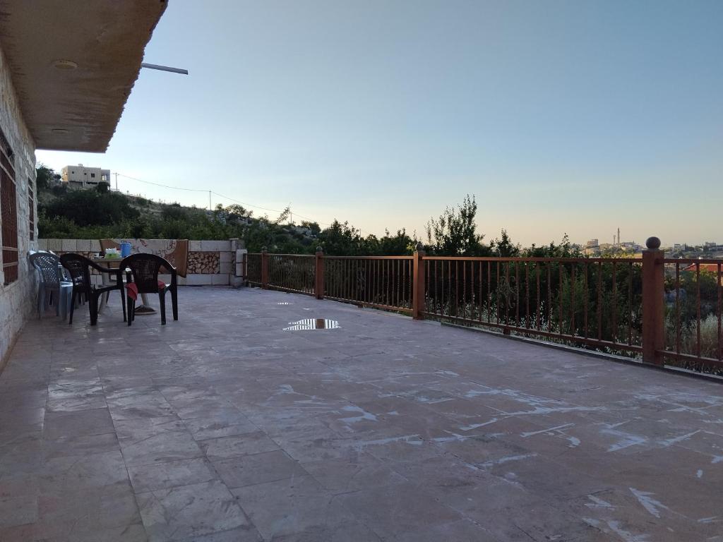 a patio with a table and chairs and a fence at The Mountain Village View اطلالة الجبل in ‘Ibbīn