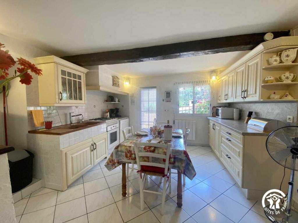 a kitchen with white cabinets and a table in it at La paraguère in Sorède