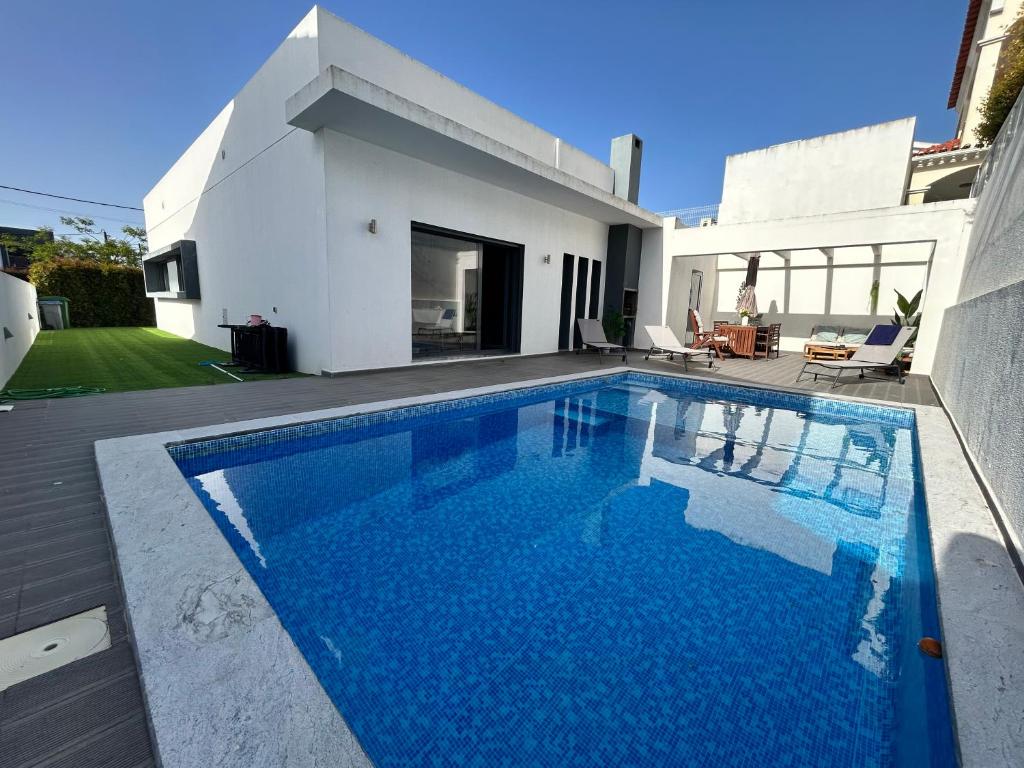 a swimming pool in front of a house at Valadares Pool Villa in Corroios