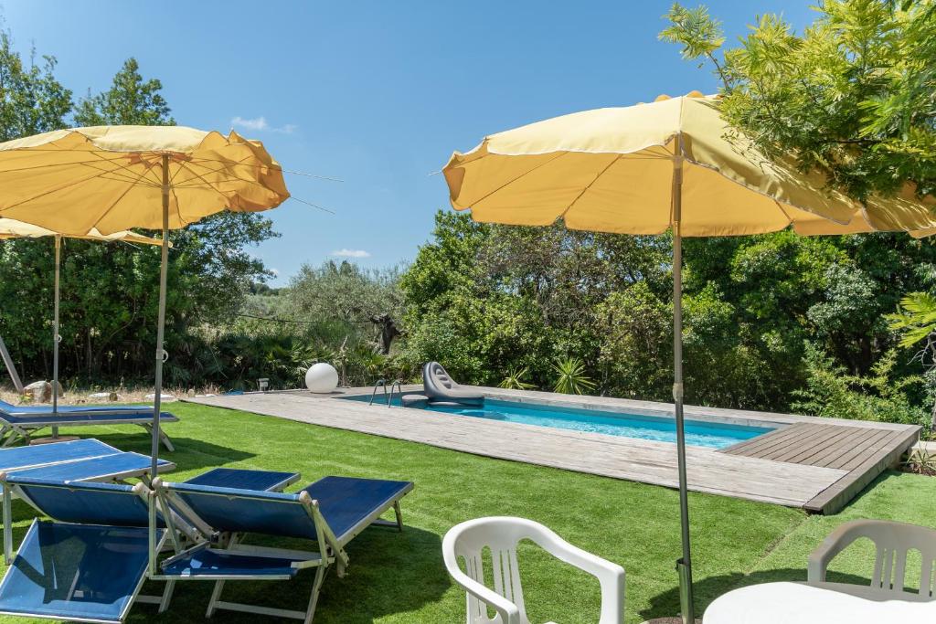 a yard with chairs and umbrellas and a swimming pool at Pugliaholidayplus - IL VILLONE NEL BOSCO in Polignano a Mare