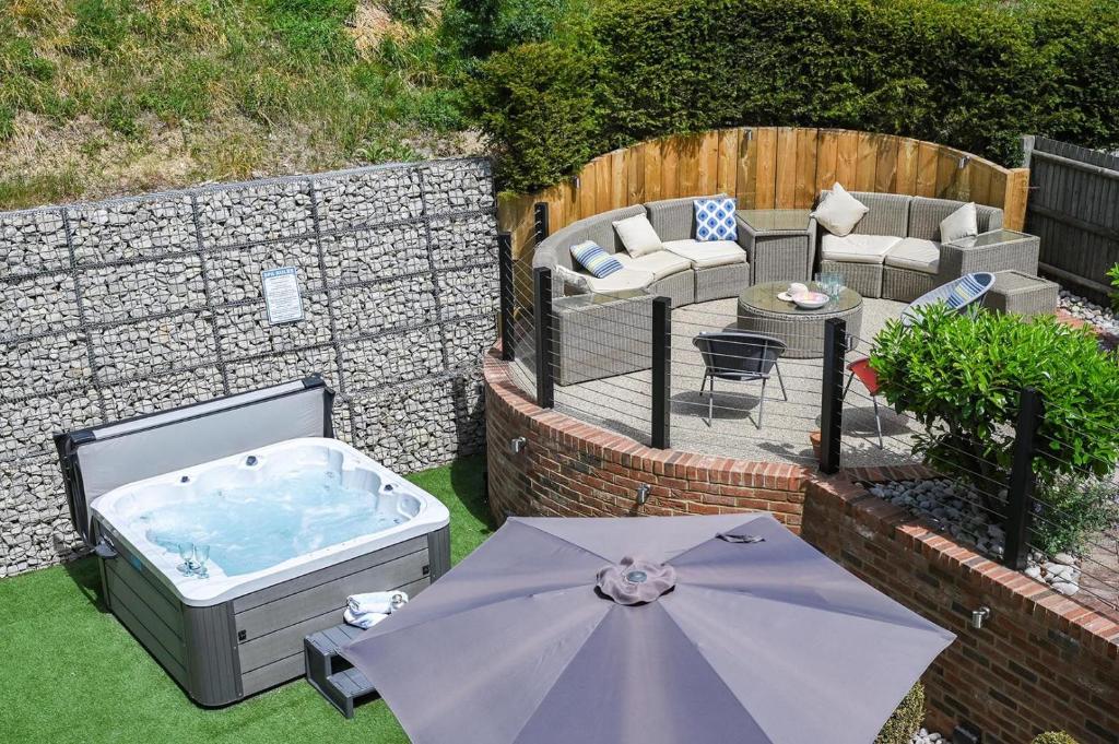 a backyard with a hot tub and a table and an umbrella at Hockley House by Bloom Stays in Folkestone
