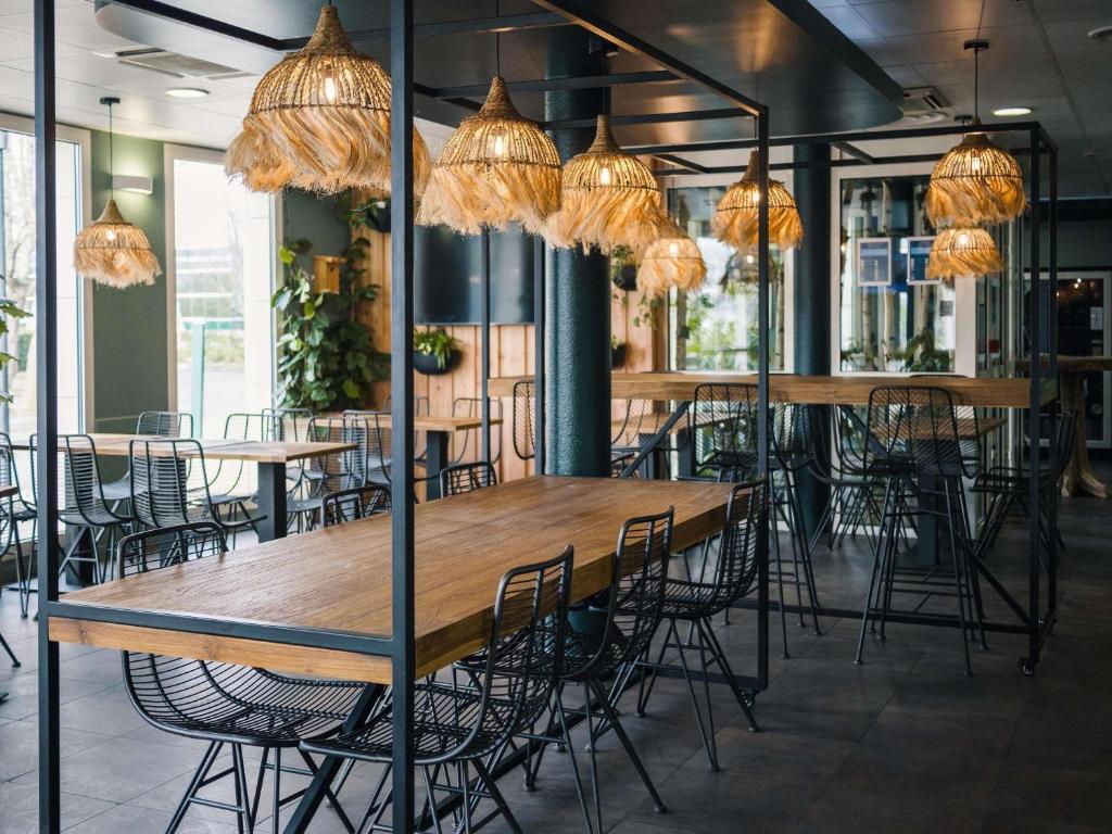 a group of tables and chairs in a room with chandeliers at ibis budget Bordeaux Aéroport in Mérignac