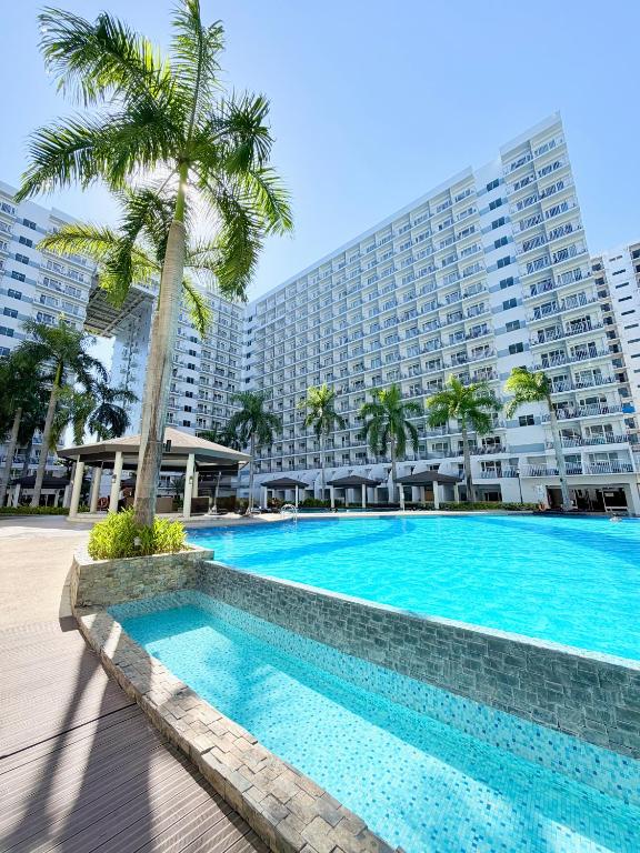 a swimming pool in front of a large building at Shell Residences Staycation MOA & NAIA by Keith in Manila