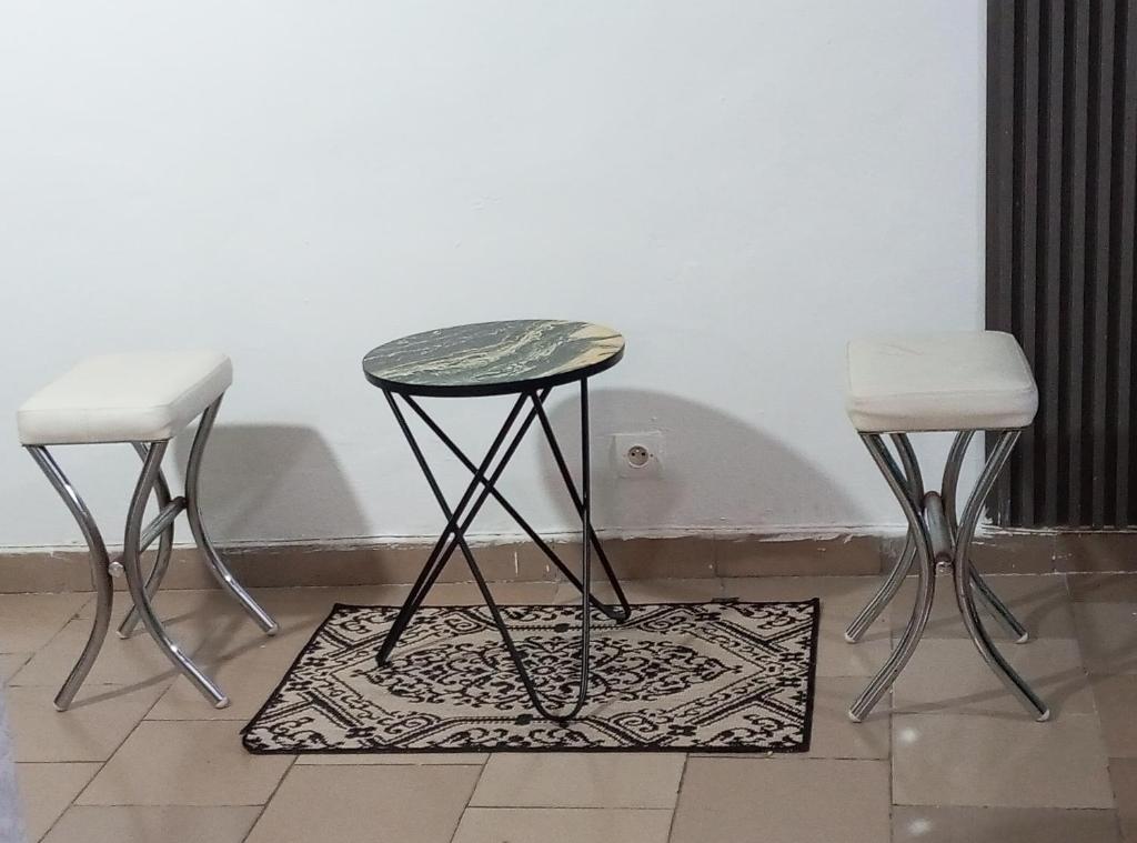 a table and two stools sitting next to a wall at Résidence cosy in Abidjan