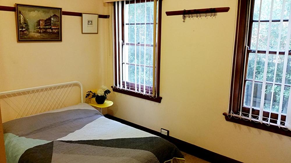 um quarto com uma cama e duas janelas em Deco Family House em Melbourne