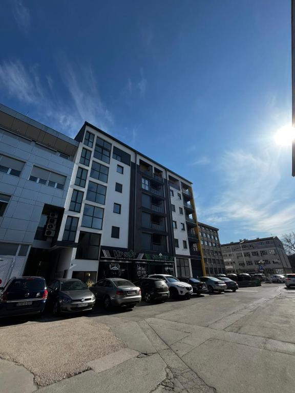 a large building with cars parked in a parking lot at City Nest, Free Parking & City Center in Prijedor