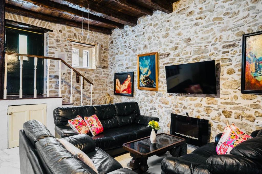 a living room with leather furniture and a stone wall at Art House Near to Saint George Beach by Konnect in Págoi