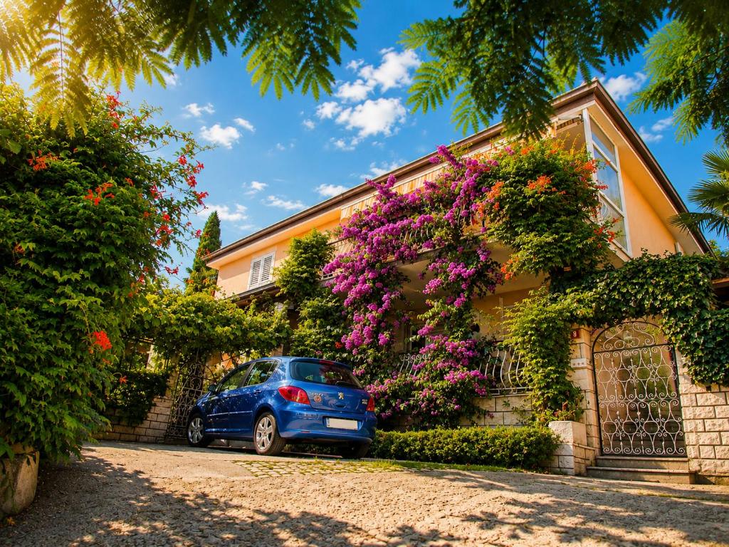 a blue car parked in front of a house with flowers at Apartments Furlan in Portorož