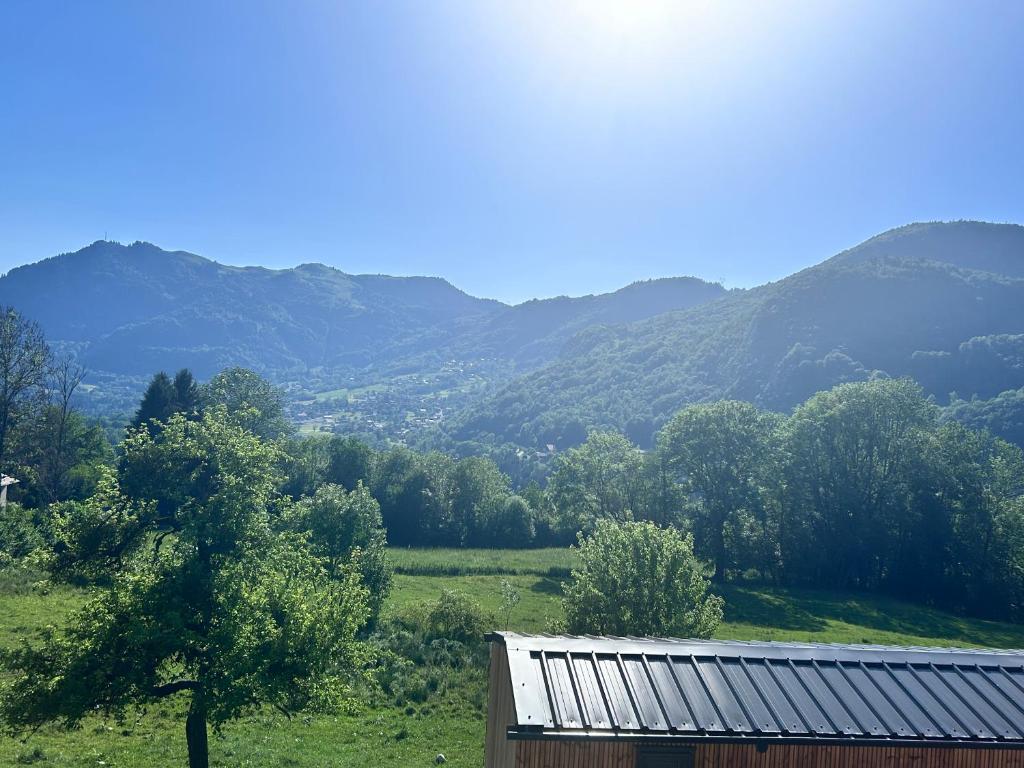 a barn in a field with mountains in the background at La Tiny de Queuvaz - Haute Savoie in Onnion