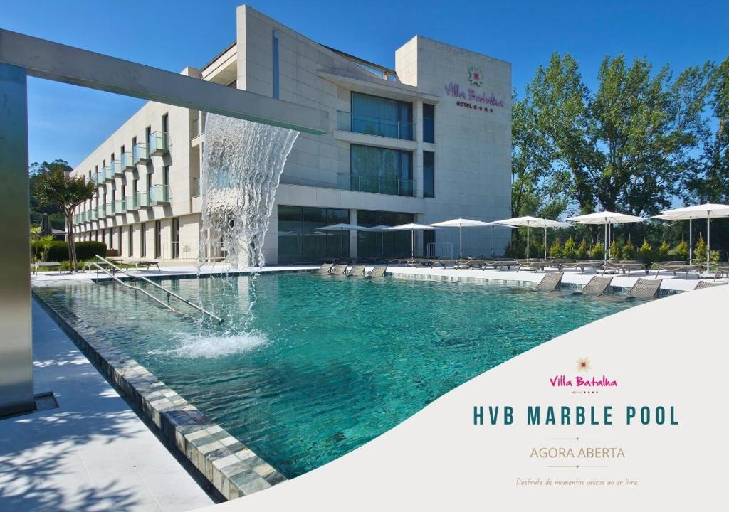 a swimming pool with a fountain in front of a building at Hotel Villa Batalha in Batalha