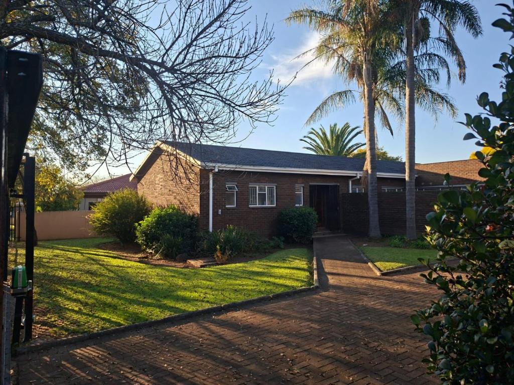a house with a palm tree and a driveway at Oolele BnB Newcastle in Newcastle