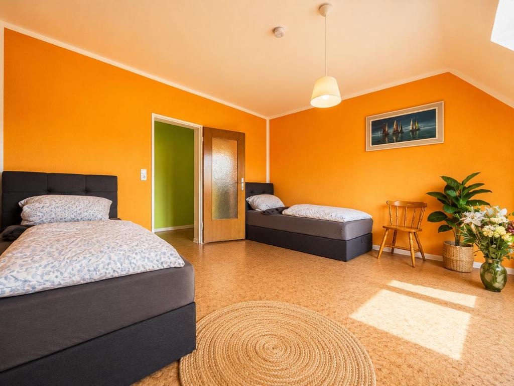 a bedroom with two beds and an orange wall at Modern Stay Apartments in Kassel