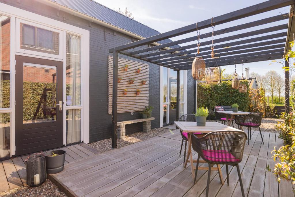 a patio with a table and chairs on a deck at Thús yn Hantum Vakantiehuisje met hottub in Friesland in Hantum