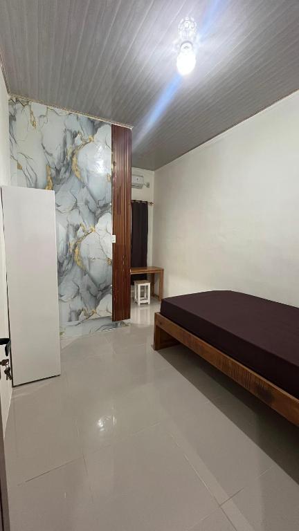 a bedroom with a bed and a stone wall at Kos Pramuka in Sunggal