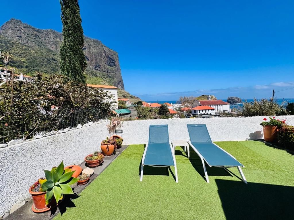 three chairs and a table on the grass at Estúdio Villa Matilde e Joaquim in Porto da Cruz