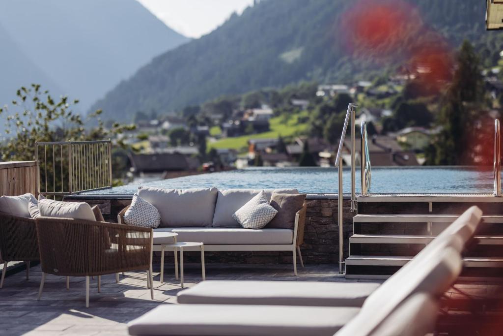 eine Couch auf einer Terrasse neben einem Gewässer in der Unterkunft Genusshotel Vermala Montafon in Sankt Gallenkirch