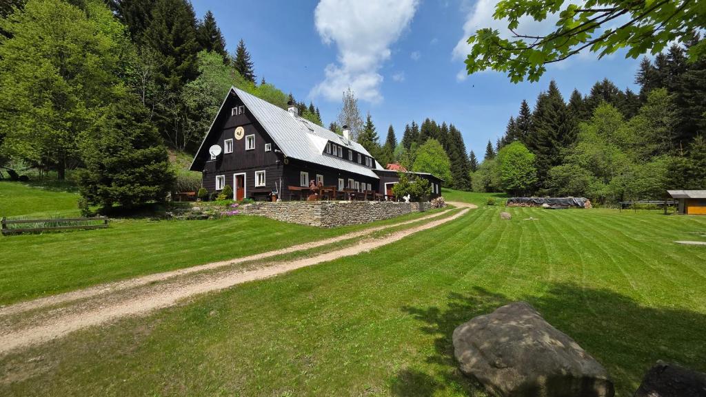 a large black house on a green field at Horská bouda U Kokrháče in Dolní Malá Úpa