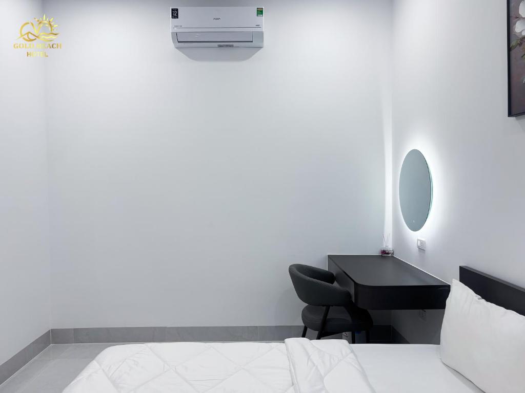 a white bedroom with a bed and a desk at Hotel Gold Beach in Phương Phi