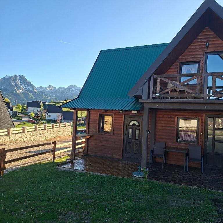a wooden cabin with a green roof and a fence at Chalet Hill Mountain Sauna in Žabljak