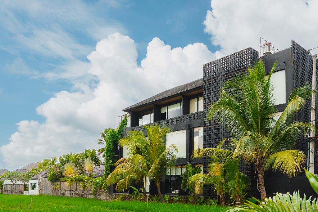 a building with palm trees in front of it at M4YA Berawa in Canggu