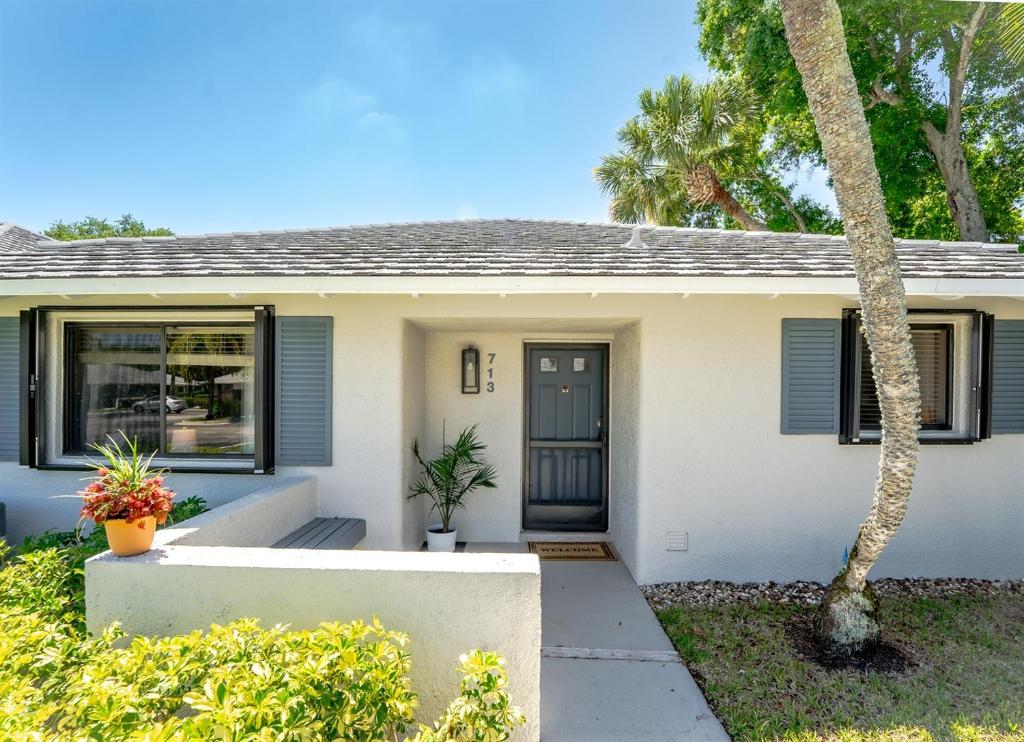 a small white house with a blue door at Upscale 2BR Townhome Golf, Pools & Lake Views in Palm Beach Gardens