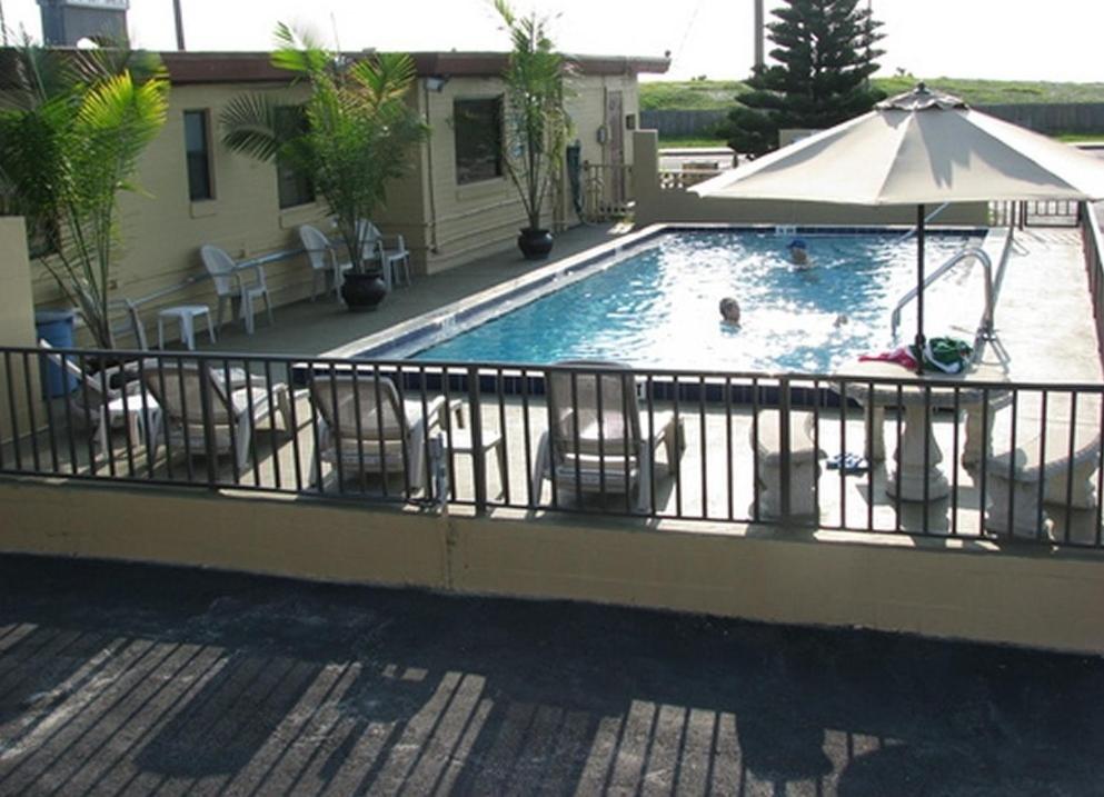 a swimming pool with chairs and an umbrella at Atlantic Economy Inn in Daytona Beach