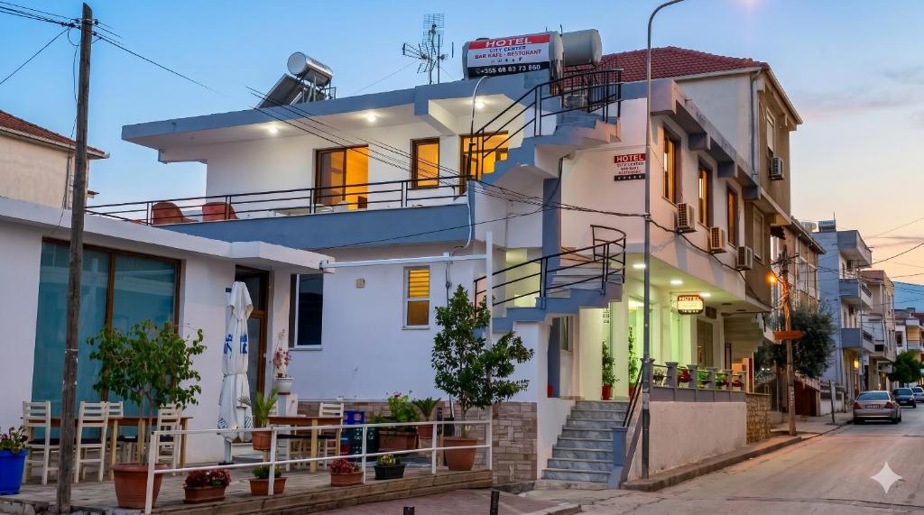 a white house with a balcony on a street at City Center Hotel in Sarandë
