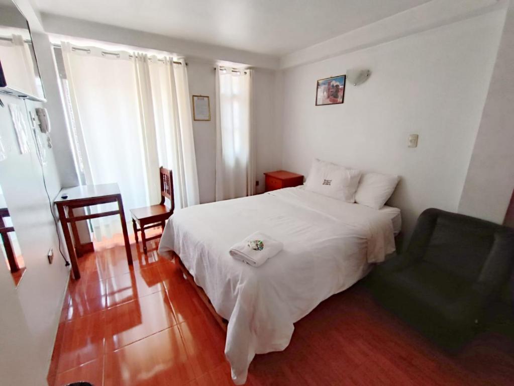 a bedroom with a white bed and a chair at Hostal El Balcon in Ayacucho