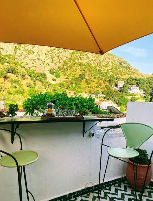 a balcony with two chairs and an umbrella at Dar SBAA in Chefchaouen