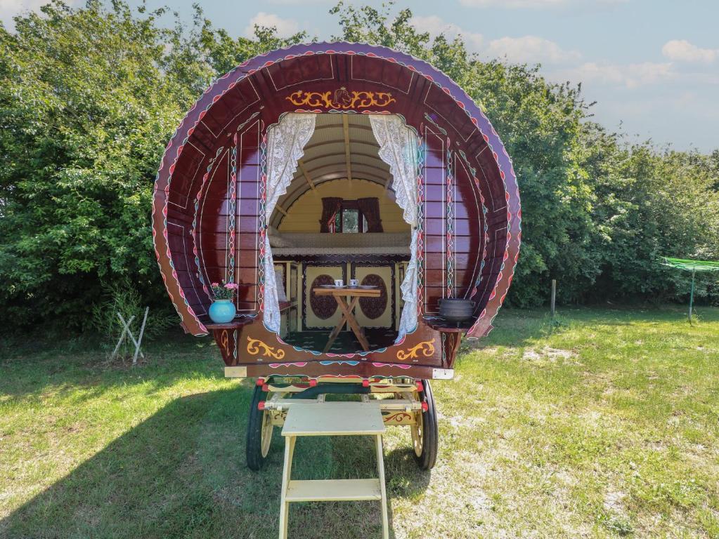 a purple carriage parked in a field with a ladder at The Bowtop Gypsy Caravan in Eye
