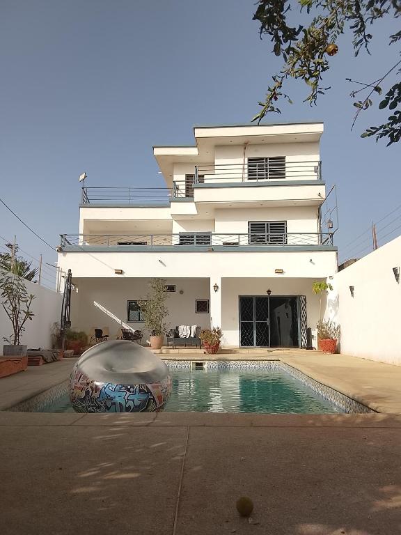 a building with a swimming pool in front of a house at Les chambres de la mangrove in Somone