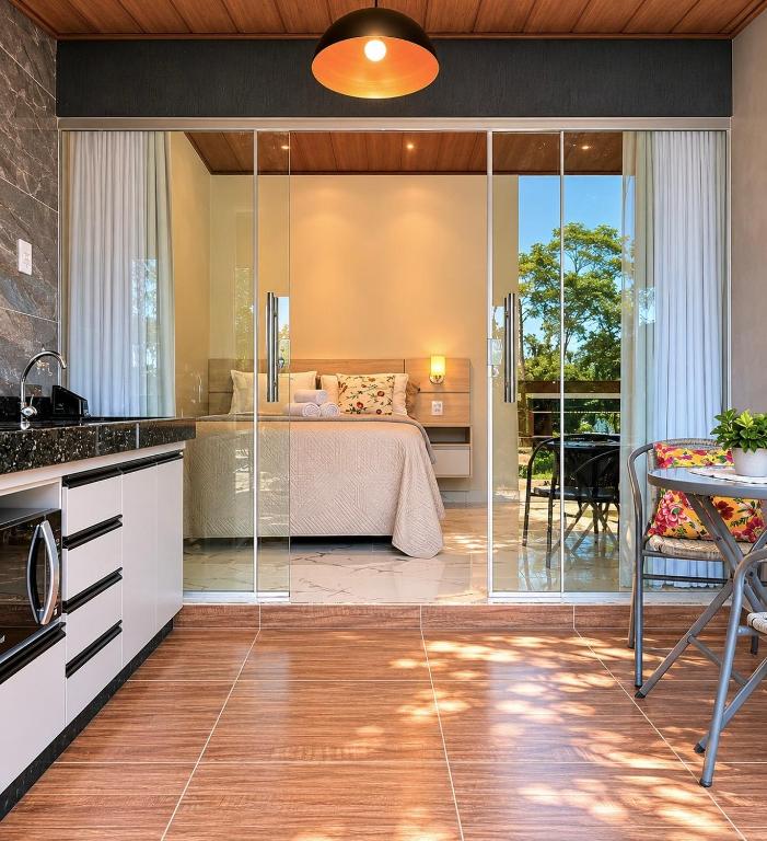 a kitchen with a glass door leading to a bedroom at Flats Araras do Vale in Colinas Do Sul