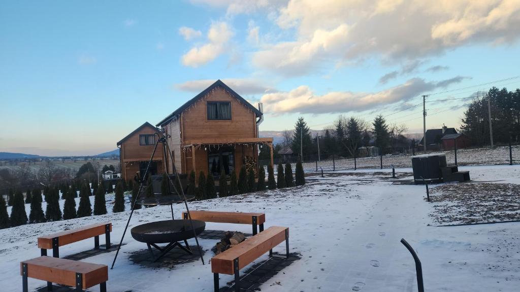 a building with a table and benches in the snow at Lipowe Love in Lipowa