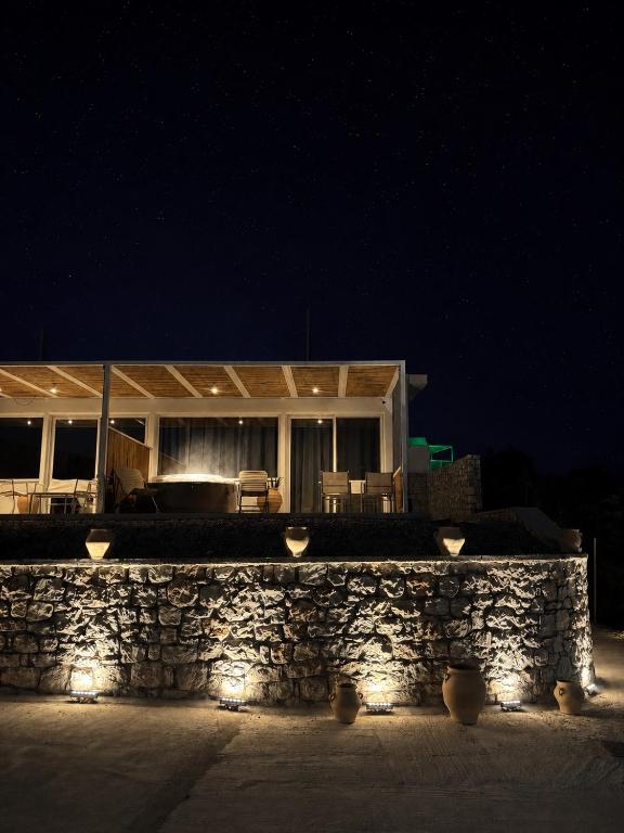 a building with a stone wall and lights at night at Almyra Suites in Archangelos