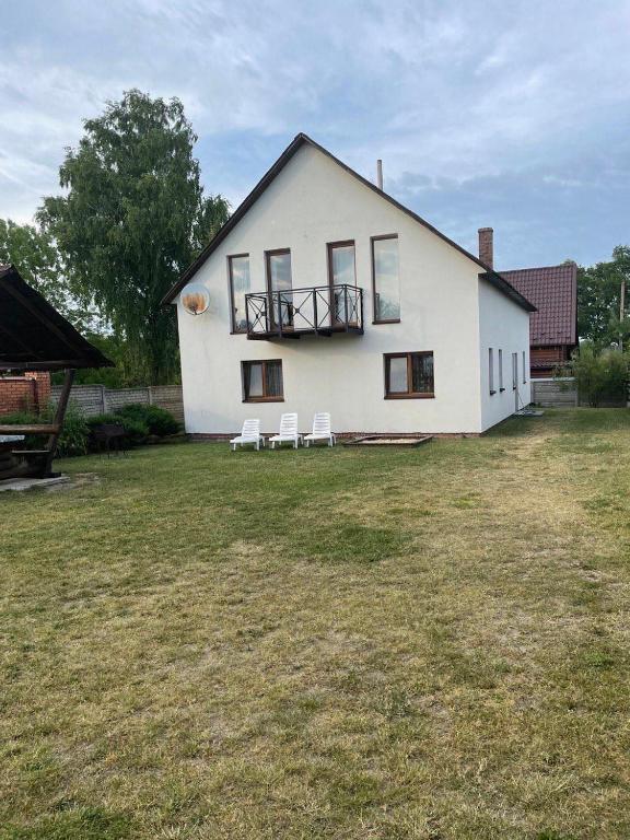 a large white house with two white chairs in the yard at Ангеліна in Svityazʼ