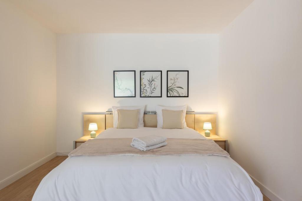 a bedroom with a white bed with three pictures on the wall at Villa Anita in Chevreuse