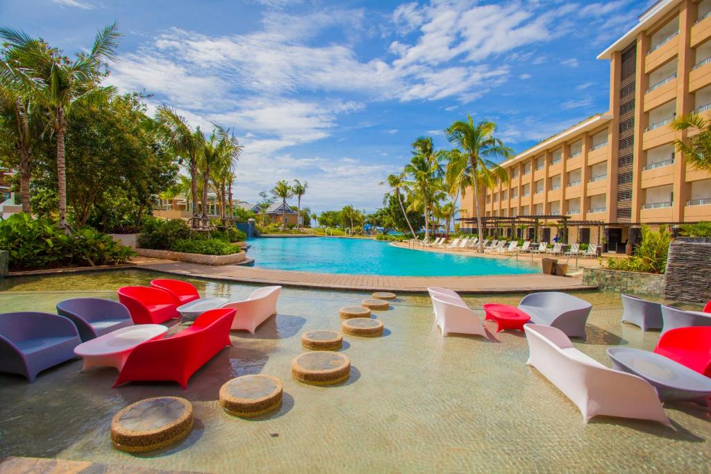 un complejo con piscina, sillas y un edificio en BE Grand Resort, Bohol, en Panglao
