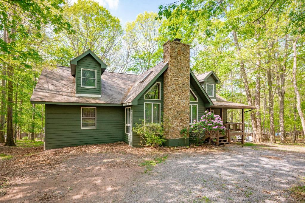 a green house in the woods with a driveway at Get Your Creek On by Railey Vacations in Swanton