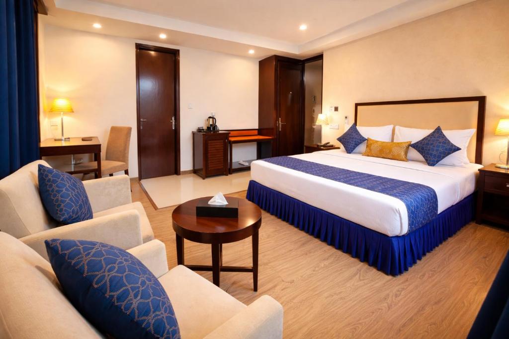 a hotel room with a king sized bed and chairs at Hotel Amber Palace in Gurgaon