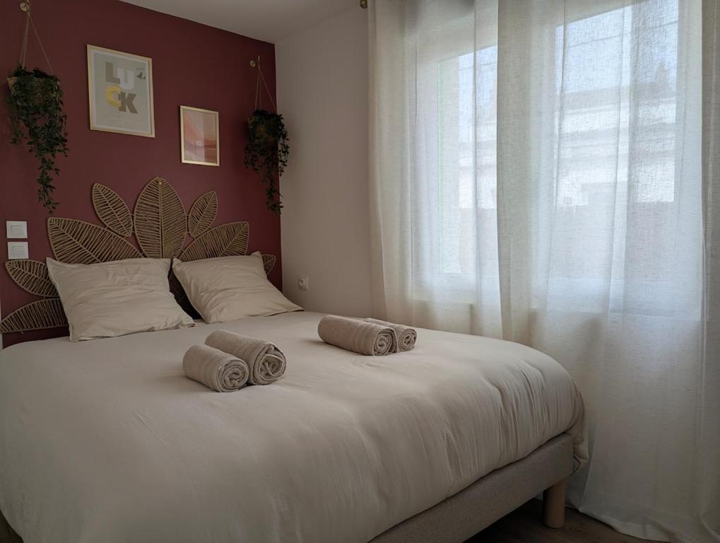 a bed with two pillows on it with a window at Studio cosy - terrasse privative - lit queen size in Berck-sur-Mer