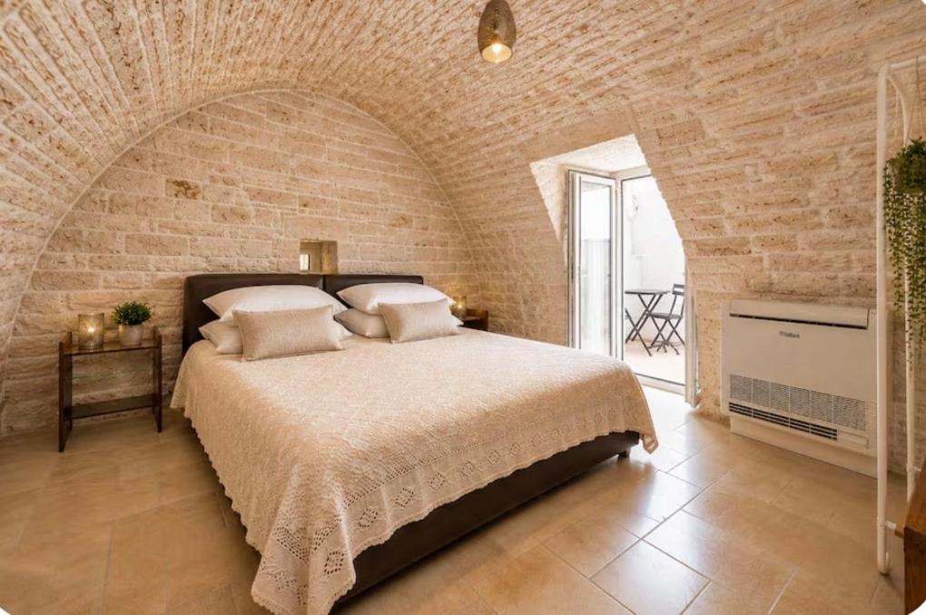 a bedroom with a large bed in a brick wall at Martine Dimore Storiche di Puglia in Martina Franca