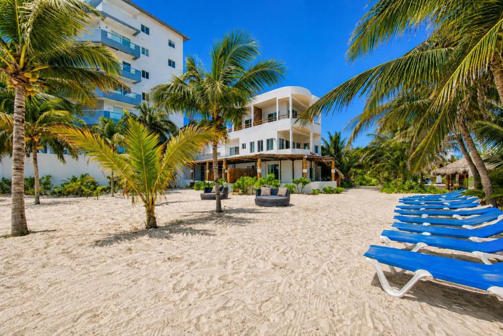 a row of blue lounge chairs on a beach at Arenika Beachfront Villa & Rooms in Puerto Morelos