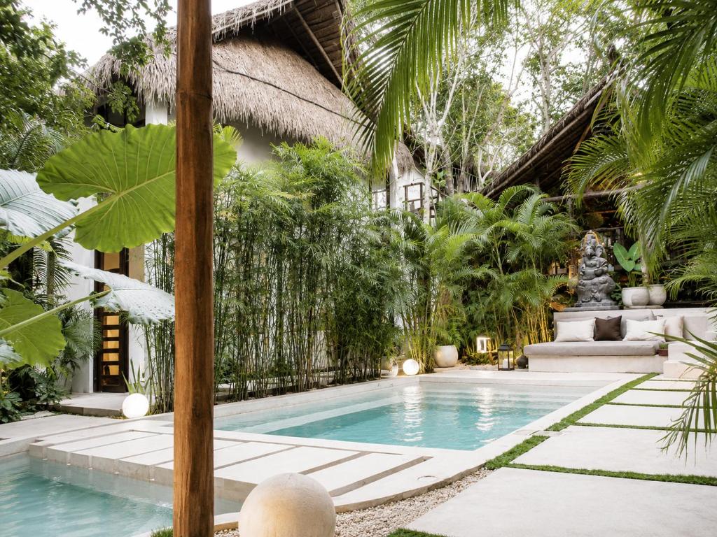 a swimming pool in front of a house with trees at Ikal Bungalows Tulum in Tulum