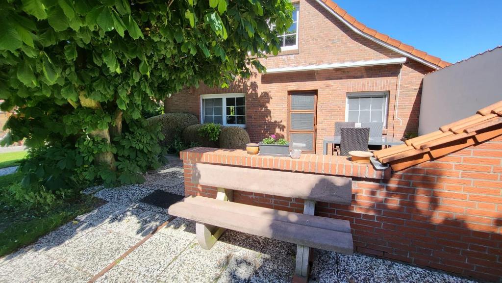 a brick wall with a bench in front of a house at Ferienwohnung Inge EG in Greetsiel