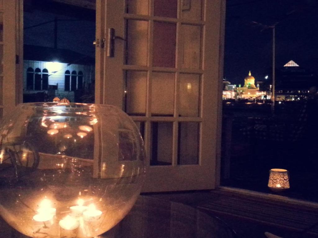 a glass vase with candles in front of a window at Kunyit 7 Lodge in Bandar Seri Begawan