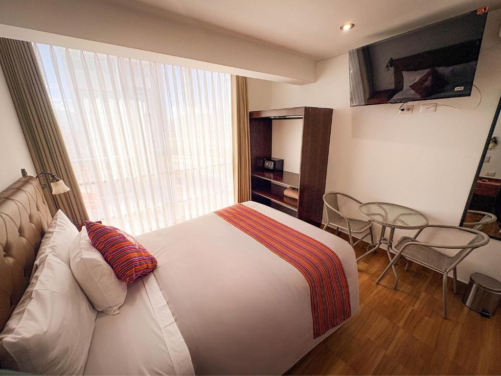 a hotel room with a bed and a table and chairs at Hotel Sky Mirador in Cusco