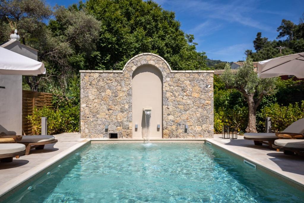 an outdoor swimming pool with a stone wall and a villa at Almyra Living - Adults Only in Agios Gordios